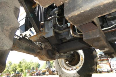 Underneath view of a Ford 6640 tractor showing drivetrain and suspension components; some hoses, frame rails, and a wheel with tire visible.