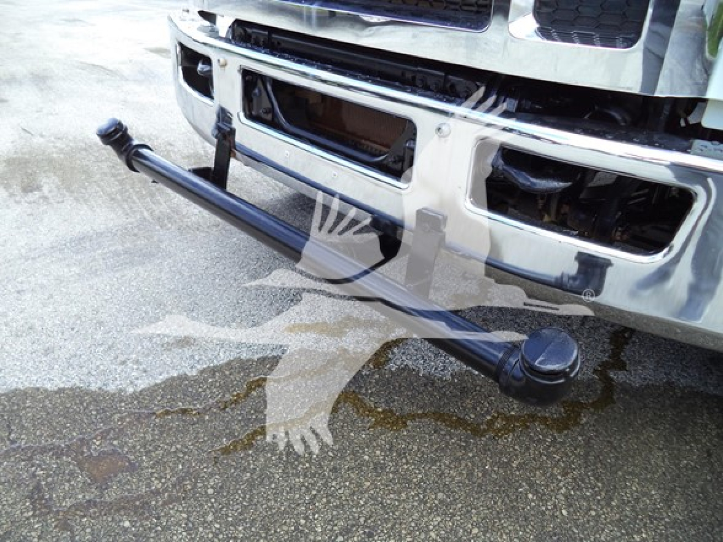 Front bumper area of a Ford F650 with a long cylindrical towing bar attached beneath the bumper.