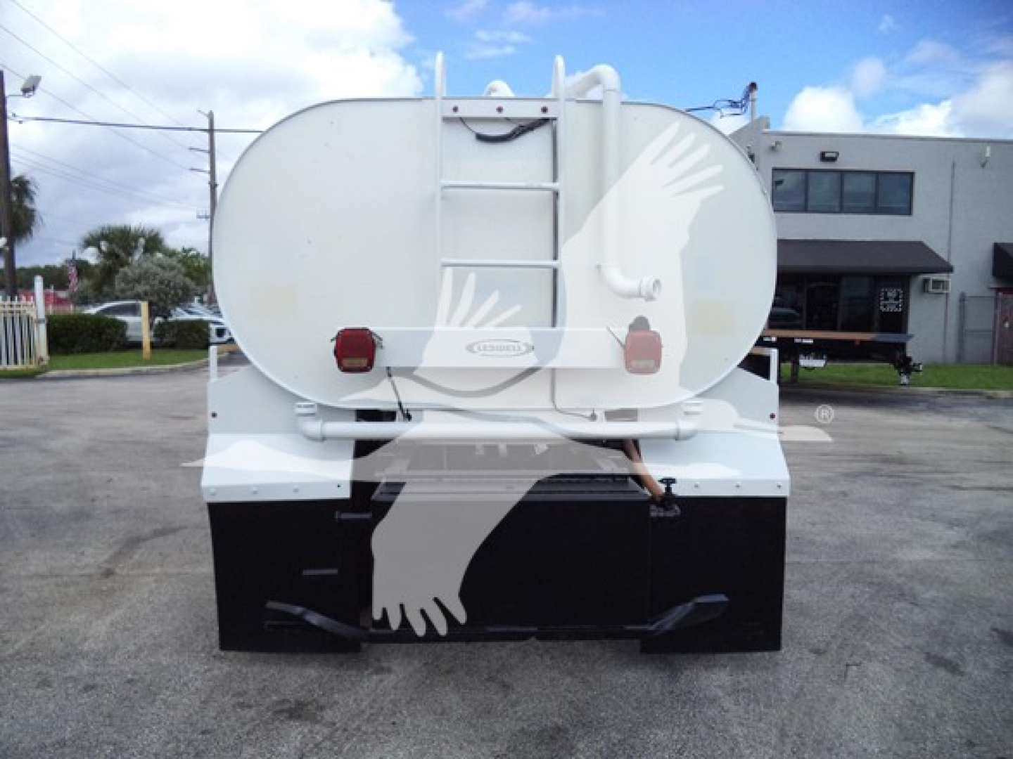 Rear of a white Ford F650 tanker truck showing round tank with decorative handprint graphics and rear bumper area.