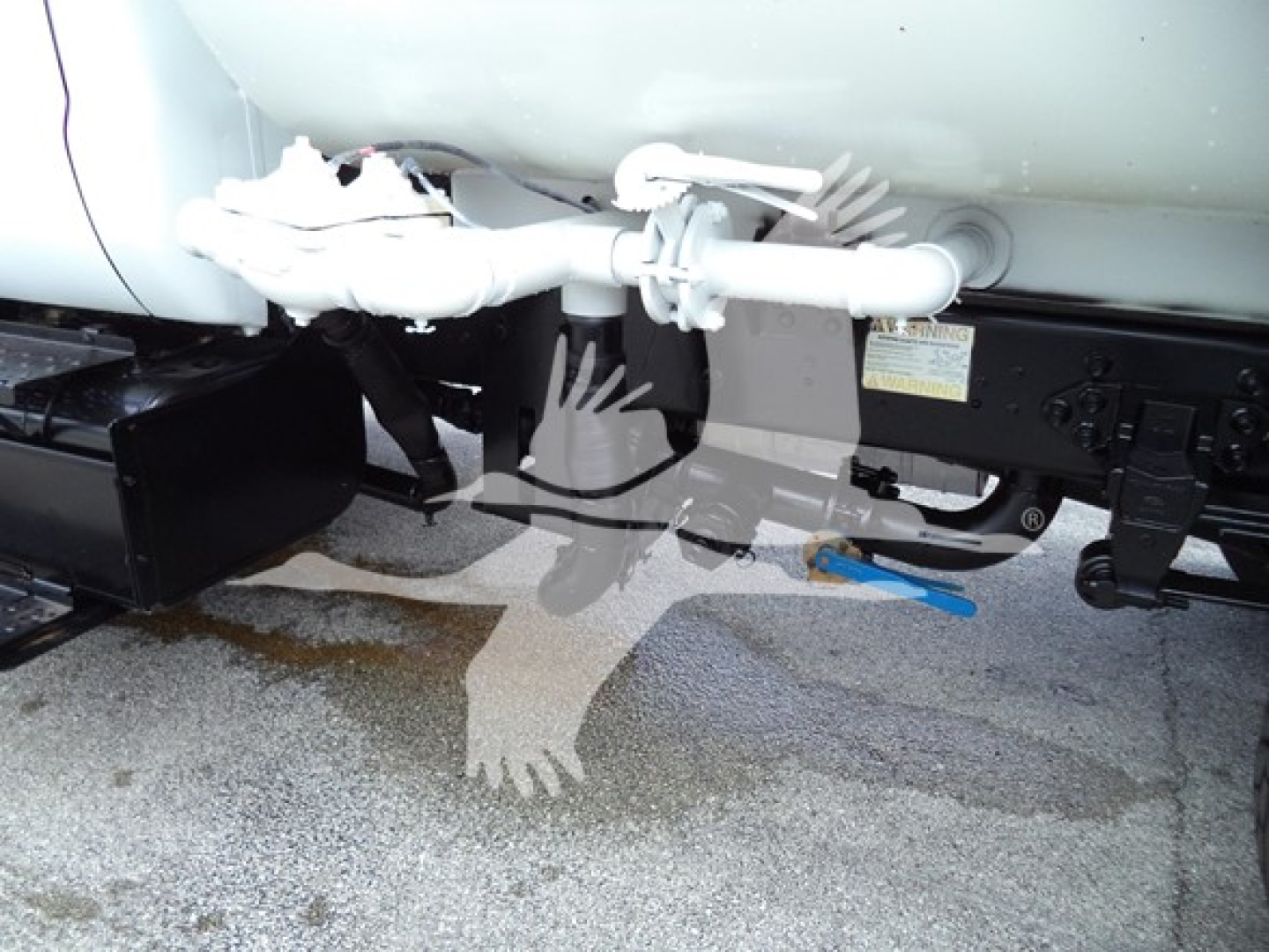 Ford F650 undercarriage showing hitch and white frame components with blue wiring and label plate.