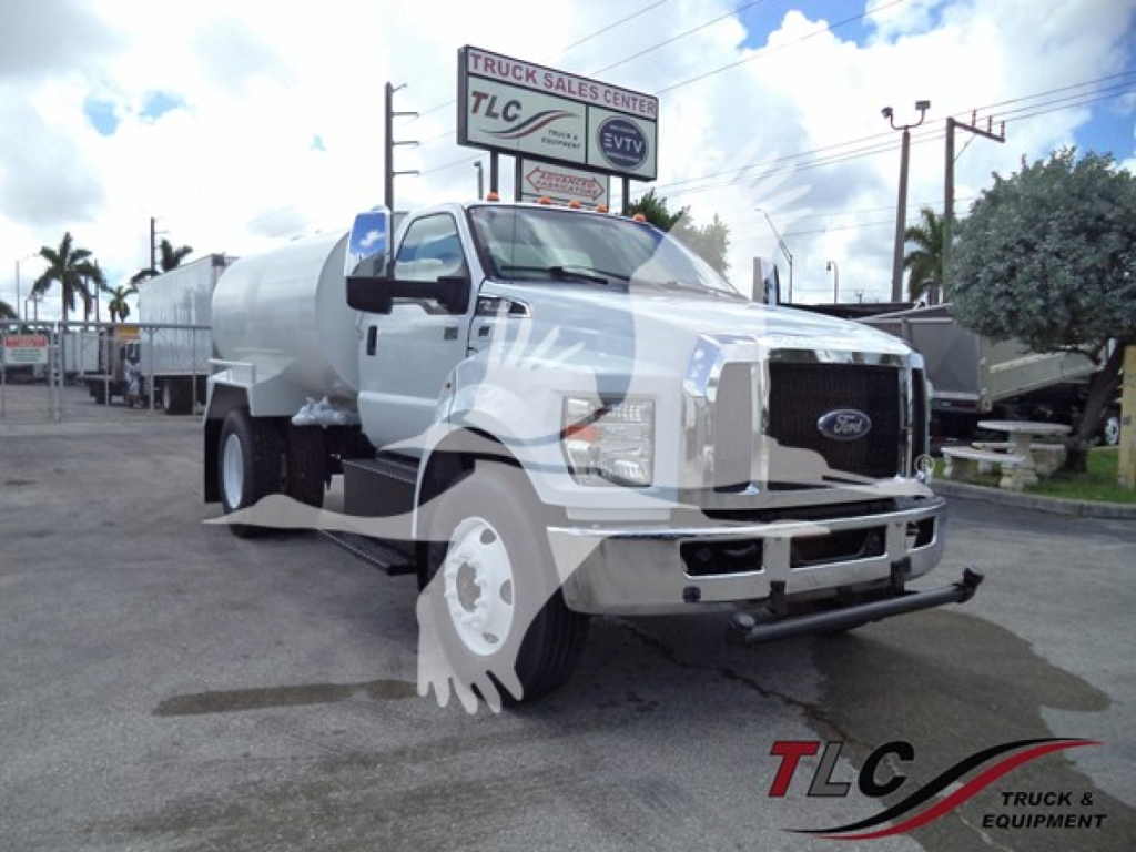 Ford F650 truck with cylindrical tank, front view showing KC Ford emblem and TLC dealership background.