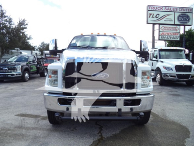 Front view of a 2017 Ford F650 truck in a used inventory lot with large grille, chrome bumper, Ford emblem, and cab lights; dealership signs and other trucks in background.