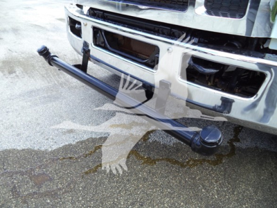 Front bumper area of a Ford F650 with a long cylindrical towing bar attached beneath the bumper.