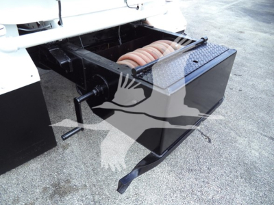 Truck side view showing a slide-out storage box with a coiled hose and mounting brackets beneath the rear of a 2017 Ford F650 chassis cab.