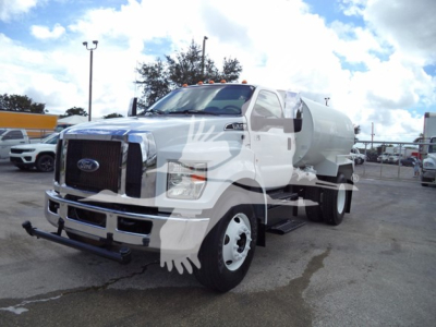 Fuel or water tanker truck view showing front grille with Ford emblem and front bumper, large cylindrical tank mounted on chassis, headlights, and side mirrors.