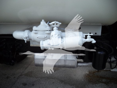 Valve assembly and filtration system under a Ford F650 truck showing a hydraulic or fuel valve with a round knob and piping, mounted near a tank.