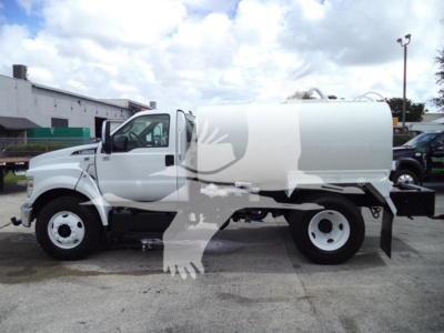 Ford F-650 water tanker truck side view showing cab and cylindrical tank with white paint.