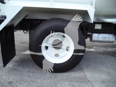 Wheel and front suspension of a Ford F650 truck showing single white steel rim and tire under truck bed side view.