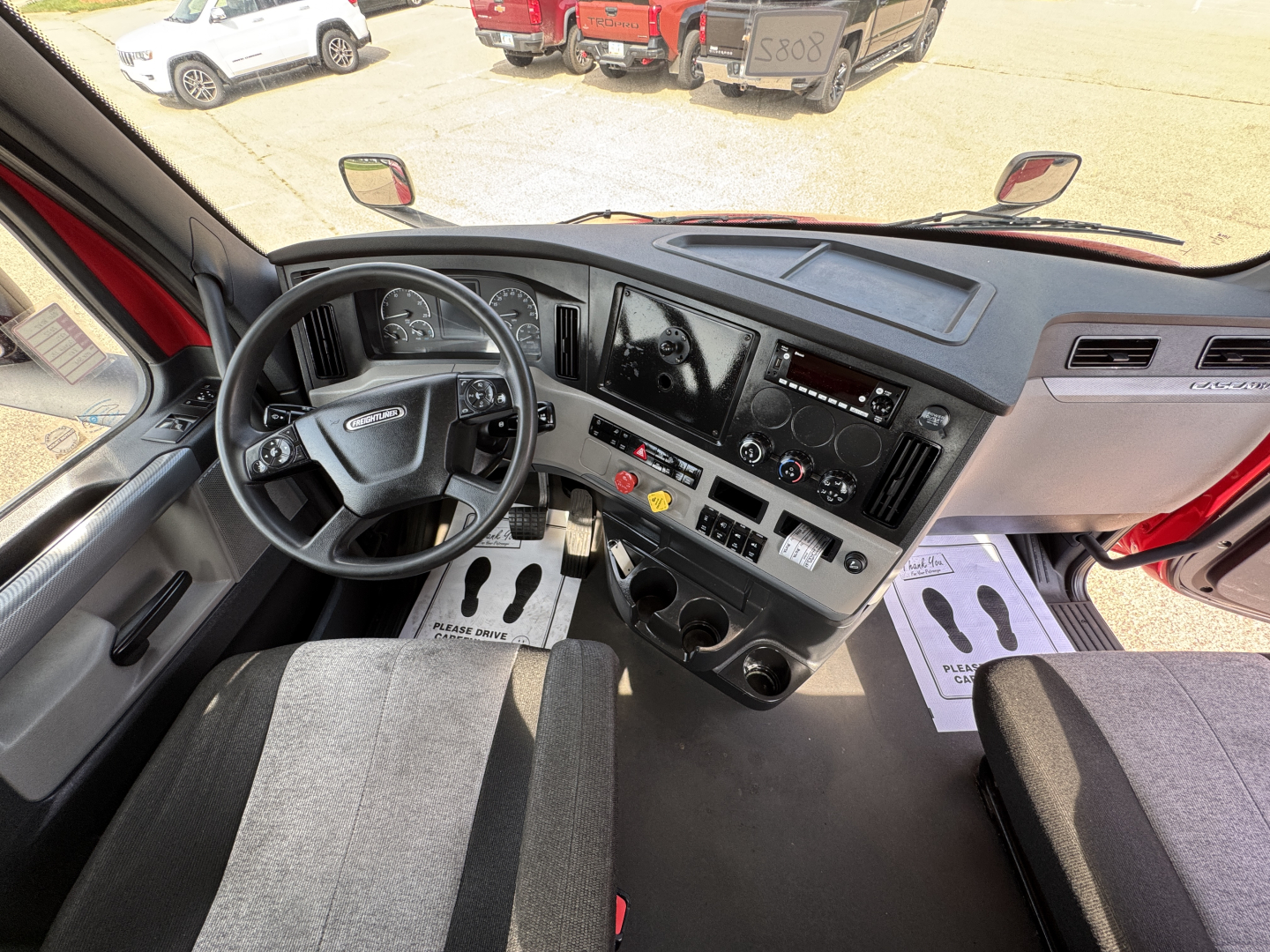 Cab interior of a 2022 Freightliner Cascadia 116 day cab showing steering wheel, dashboard, and seating area with controls and gauges.