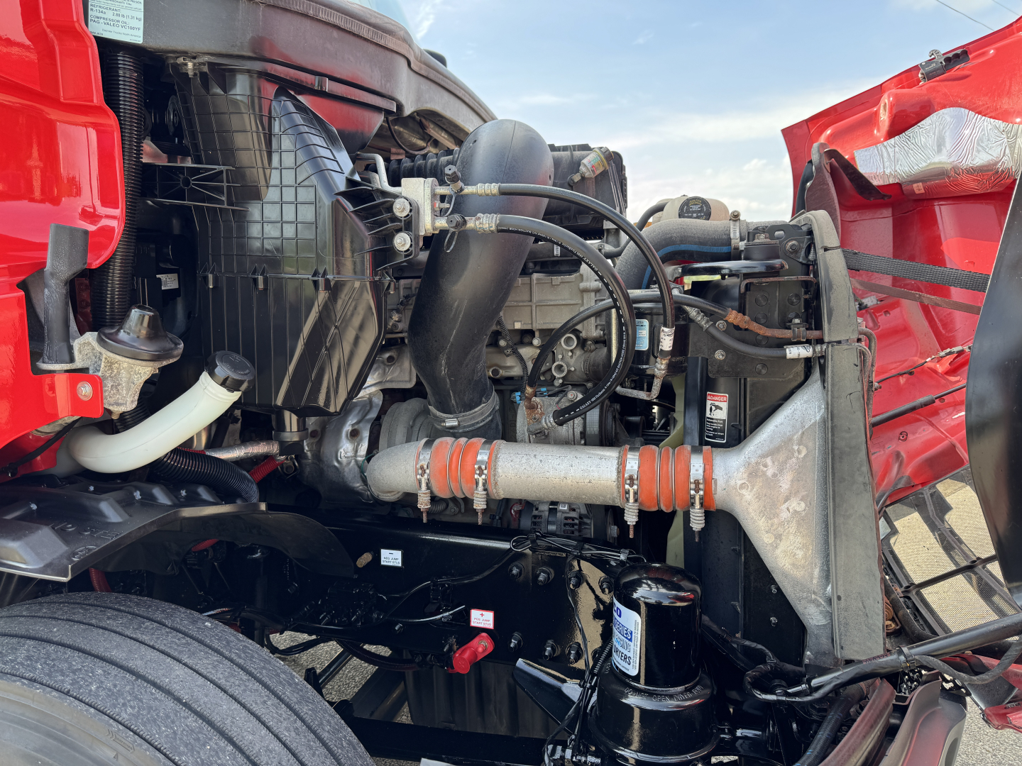 Freightliner Cascadia 116 engine bay view showing radiator, hoses, aluminum intercooler pipe, coolant reservoir, and hydraulic lines.
