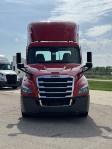 Front view of a red 2022 Freightliner Cascadia 116 day cab truck showing grille, headlights, and large overhead sleeper cab.