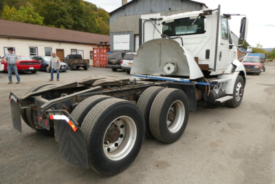 International ProStar+ 113 daycab chassis showing rear twin rear axles and exposed frame with cab in background. Stock number 1006256 visible.