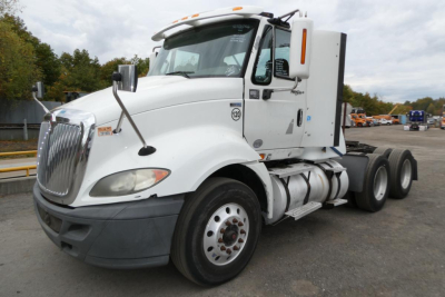 International ProStar+ 113 daycab tractor in white, front three-quarter view showing chrome grille, dual fuel tanks, and sleeper cab with steps.