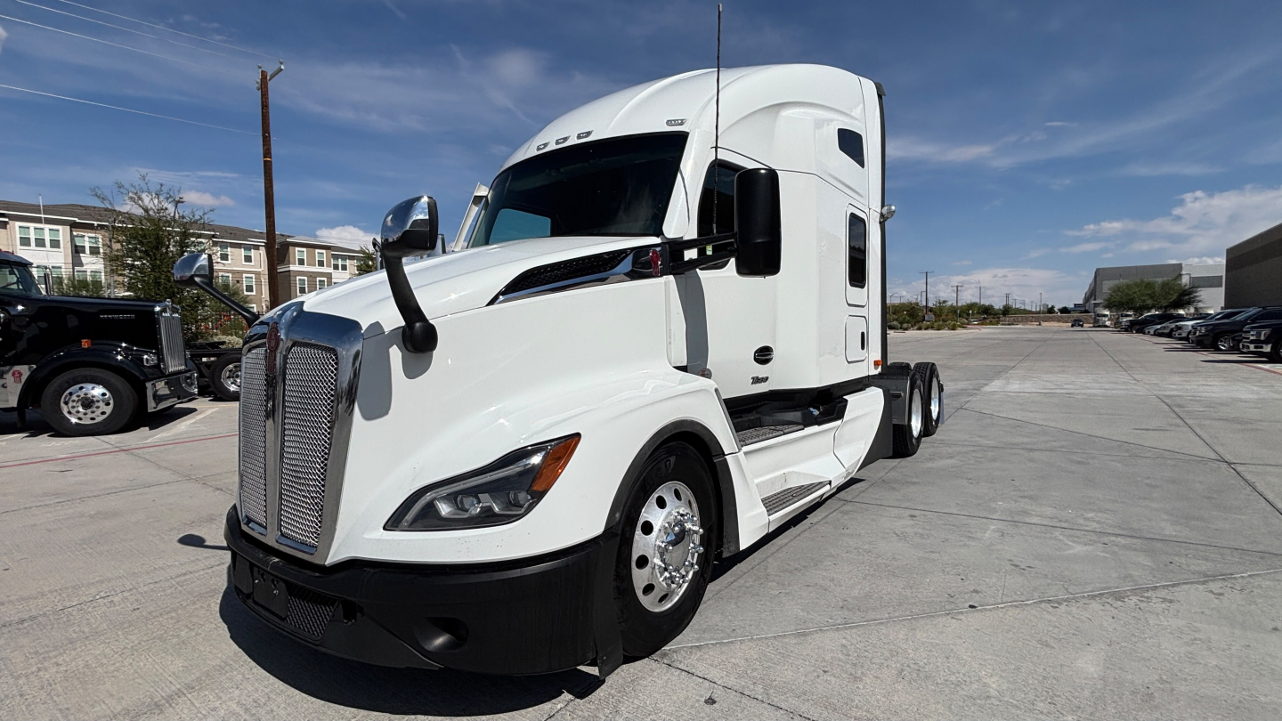 Kenworth T680 tractor in white, front-left view, showing cab and sleeper with large grille and aerodynamic mirrors.