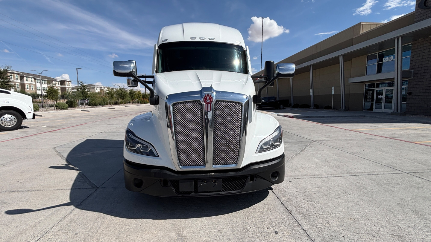 Kenworth T680 truck front view with grille, headlights, and Kenworth emblem in a parking lot.