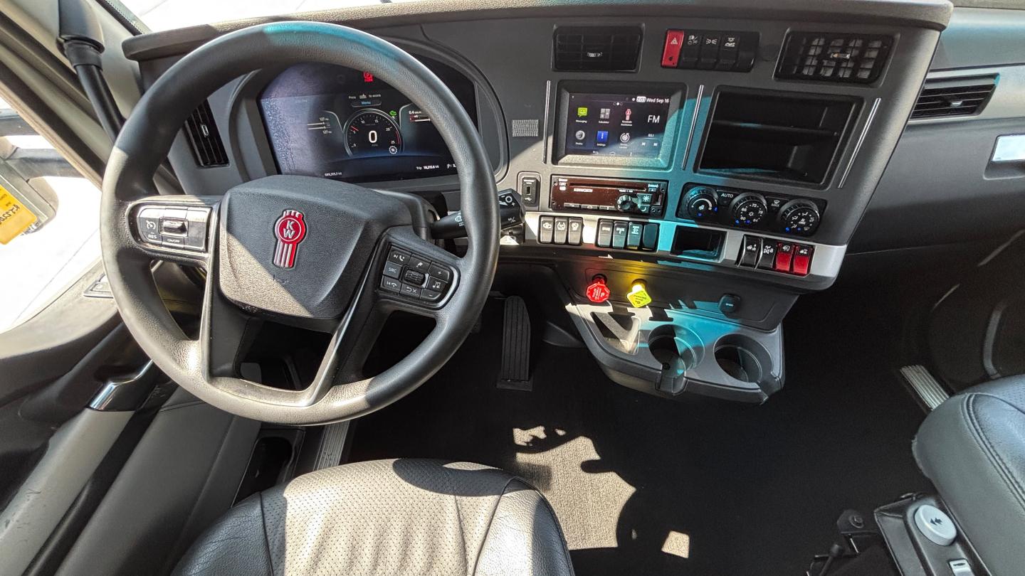Kenworth T680 interior showing steering wheel, dashboard, and center console with controls and digital display.
