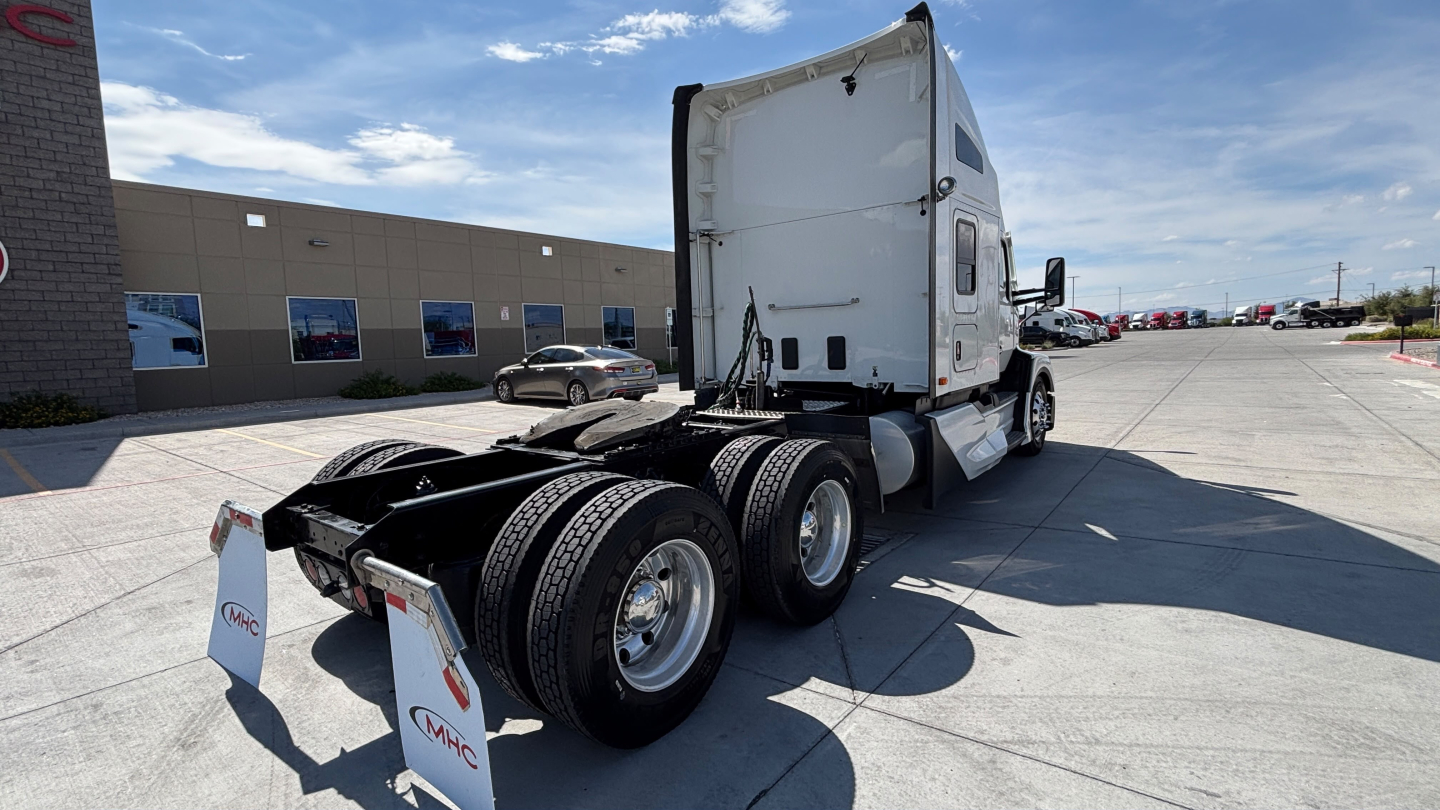 Kenworth T680 tractor in a lot showing rear view with dual rear axles and white sleeper cab.