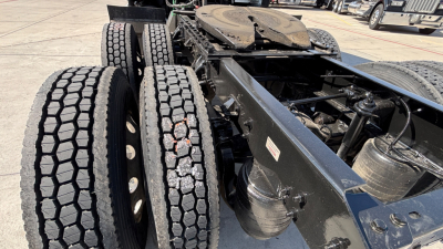Kenworth truck chassis with dual rear axles and spare tire rack showing heavy-duty wheels and suspension components.