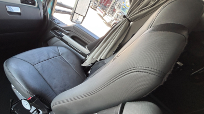 Kenworth T680 truck interior showing front seat and partition with grey upholstery, curtain behind seat. Visible text not legible on components.