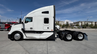 Truck side profile showing 2024 Kenworth T680 conventional sleeper, white exterior, sleeper cab, dual rear axles, chrome wheels.