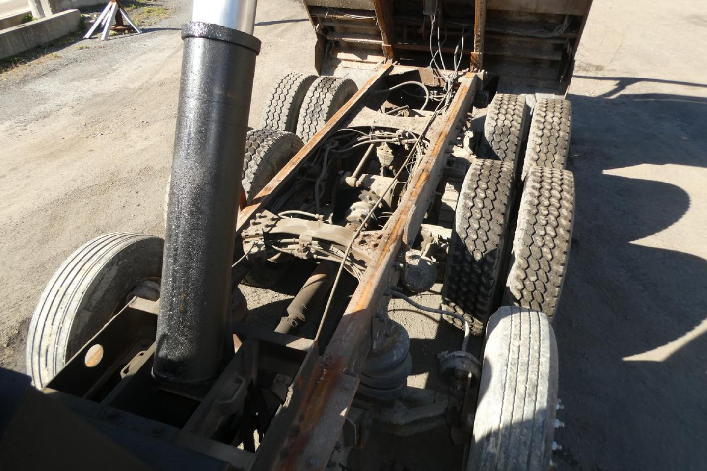 Chassis view of a 2001 Mack RD688S dump truck showing exposed frame, drive axles, and hydraulic cylinder, with wheels and suspension visible.