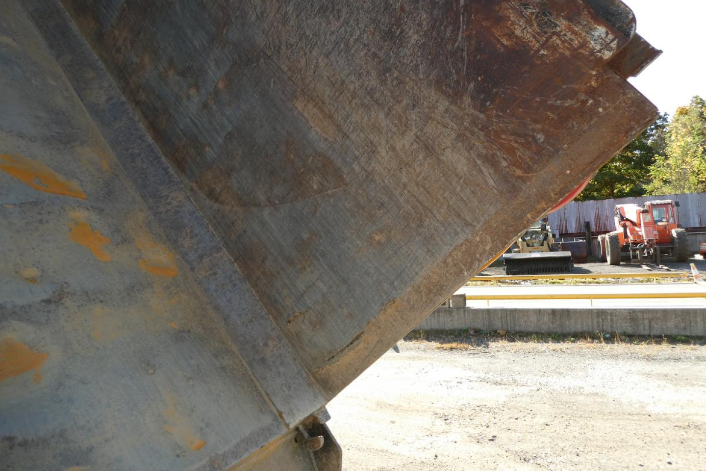 Dump truck bed interior showing steel surface with rust patina and edge of dump body in sunlight