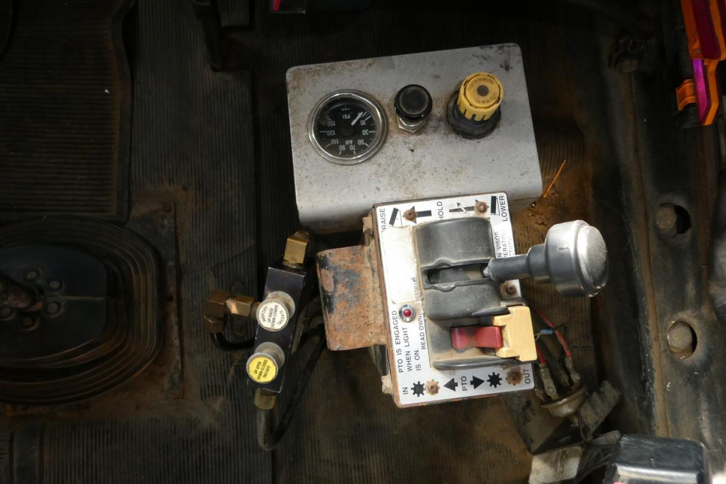 Mack RD688S truck interior view showing gauge cluster, hydraulic valve block, and control panel with yellow cap and hoses.