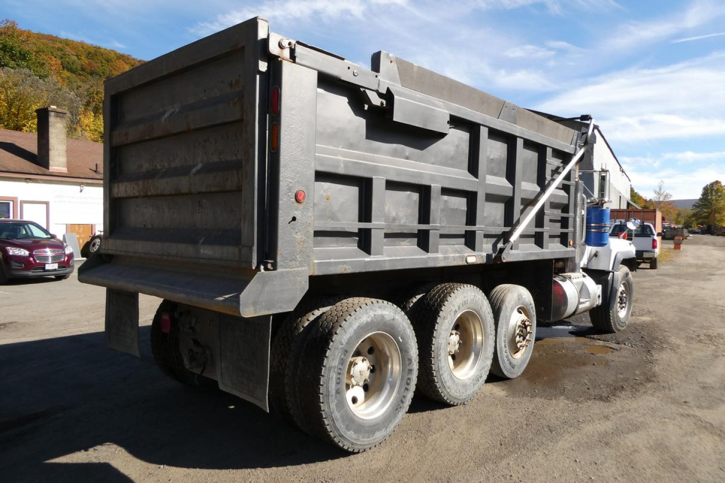 Dump truck with black dump bed and tandem rear axles visible, Mack RD688S model. Side view showing truck bed and frame.