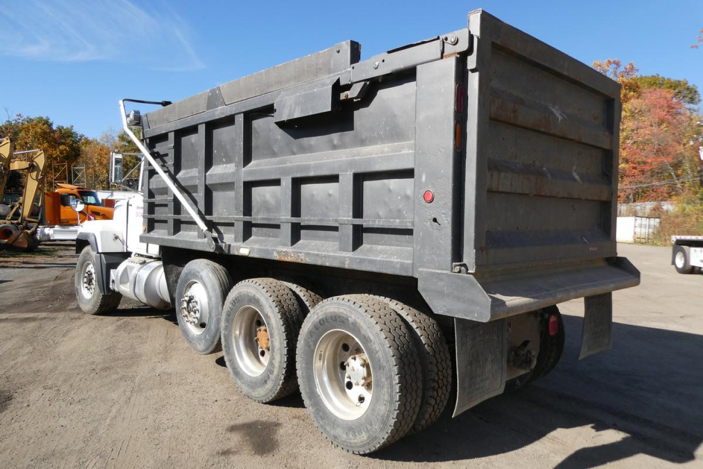 Dump truck bed of a Mack RD688S in-service with dual rear axles and hydraulic tailgate. Visible steel dump body, wheels, and mud flaps.