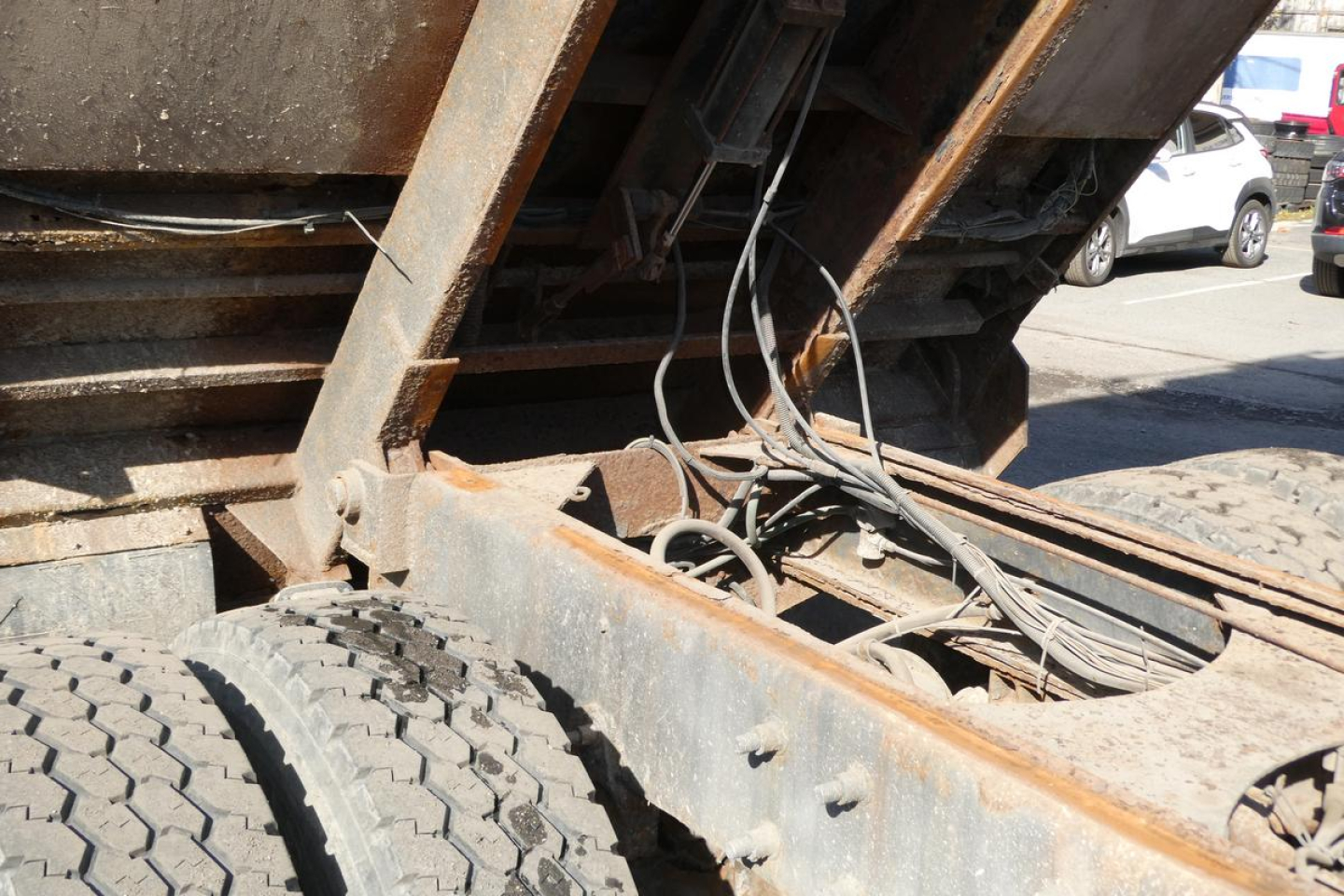 Dump truck chassis showing rear frame rails with exposed wiring and drivetrain components.