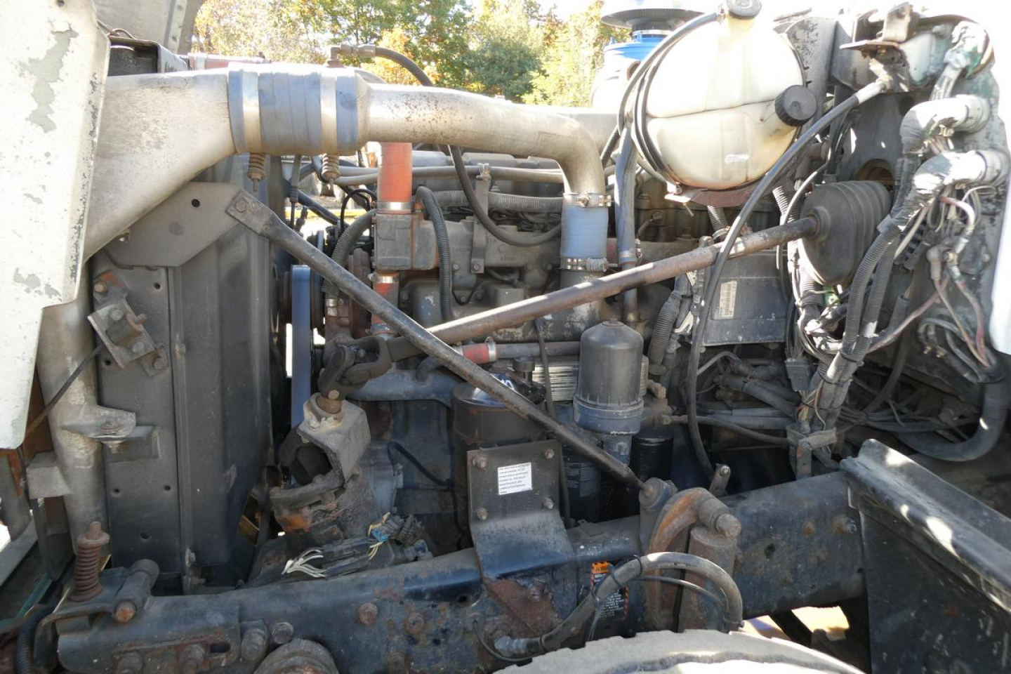 Mack RD688S engine bay showing radiator, hoses, and hydraulic lines with various components.