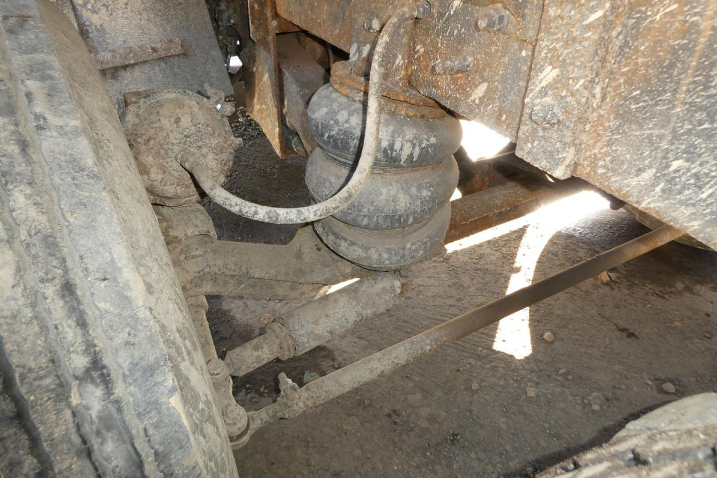 Mack RD688S dump truck undercarriage showing suspension components and hoses with dirt and grime.