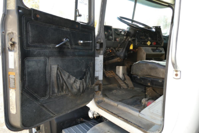 Truck cab interior of a 2001 Mack RD688S showing driver's door open, steering wheel, dashboard, and worn seat.