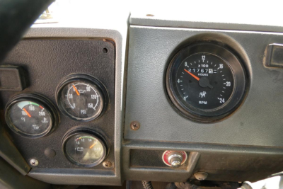 Dashboard of a 2001 Mack RD688S showing multiple gauges including air pressure gauges and RPM gauge; visible text includes RPM 'x 100' and 'Mack' branding on gauge; small red switch and various knobs.