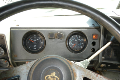Dashboard view of a Mack RD688S dump truck showing analog gauges including RPM and speedometer, steering wheel, and indicator lights.
