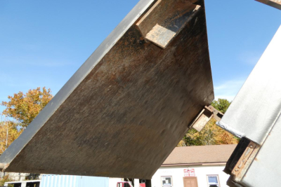 Flatbed dump truck component showing metal bed edge and support frame.