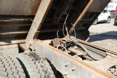 Dump truck chassis showing rear frame rails with exposed wiring and drivetrain components.