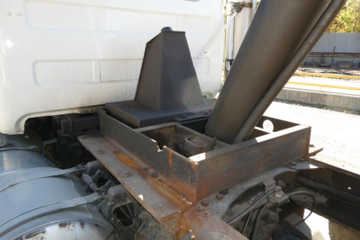 Truck chassis and mounting hardware near the cab of a 2001 Mack RD688S dump truck showing a rust-colored frame, hydraulic components, and a metal support structure.