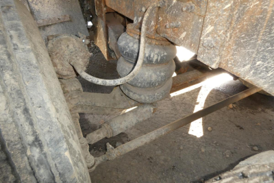 Mack RD688S dump truck undercarriage showing suspension components and hoses with dirt and grime.