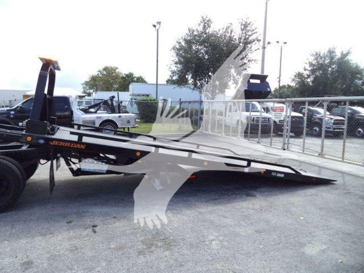 Truck rollback flatbed with a tilt bed in a dealership lot, side view showing ramp extensions and loading deck, Chevrolet Silverado 6500HD branding not visible