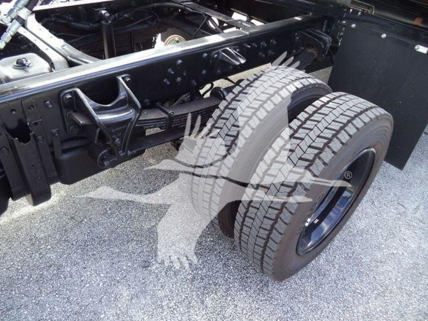 Truck chassis with dual rear wheels showing suspension and frame components.