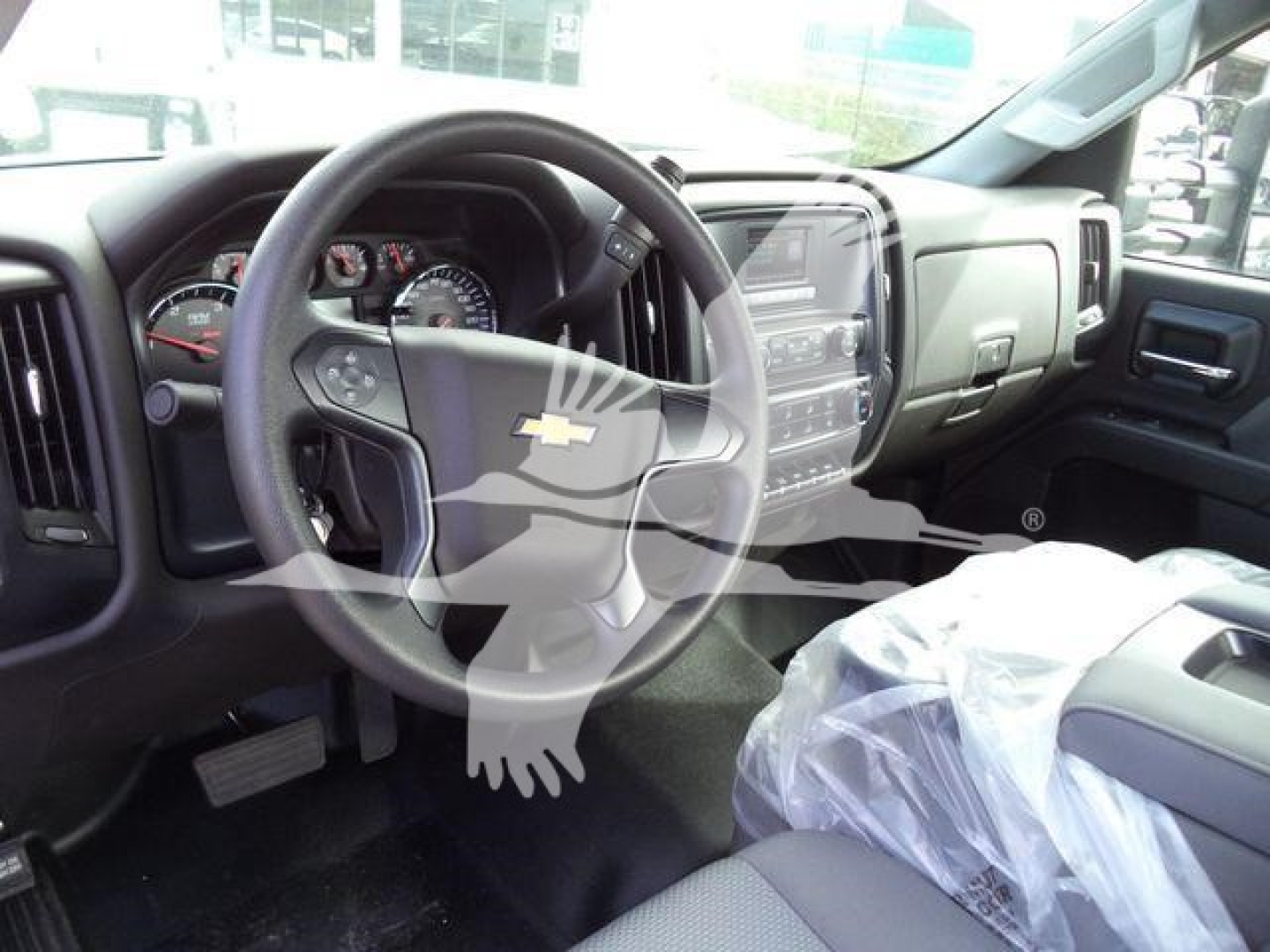 Dashboard and steering wheel of a Chevrolet Silverado 6500HD medium-duty truck with a plastic-covered seat and center console.