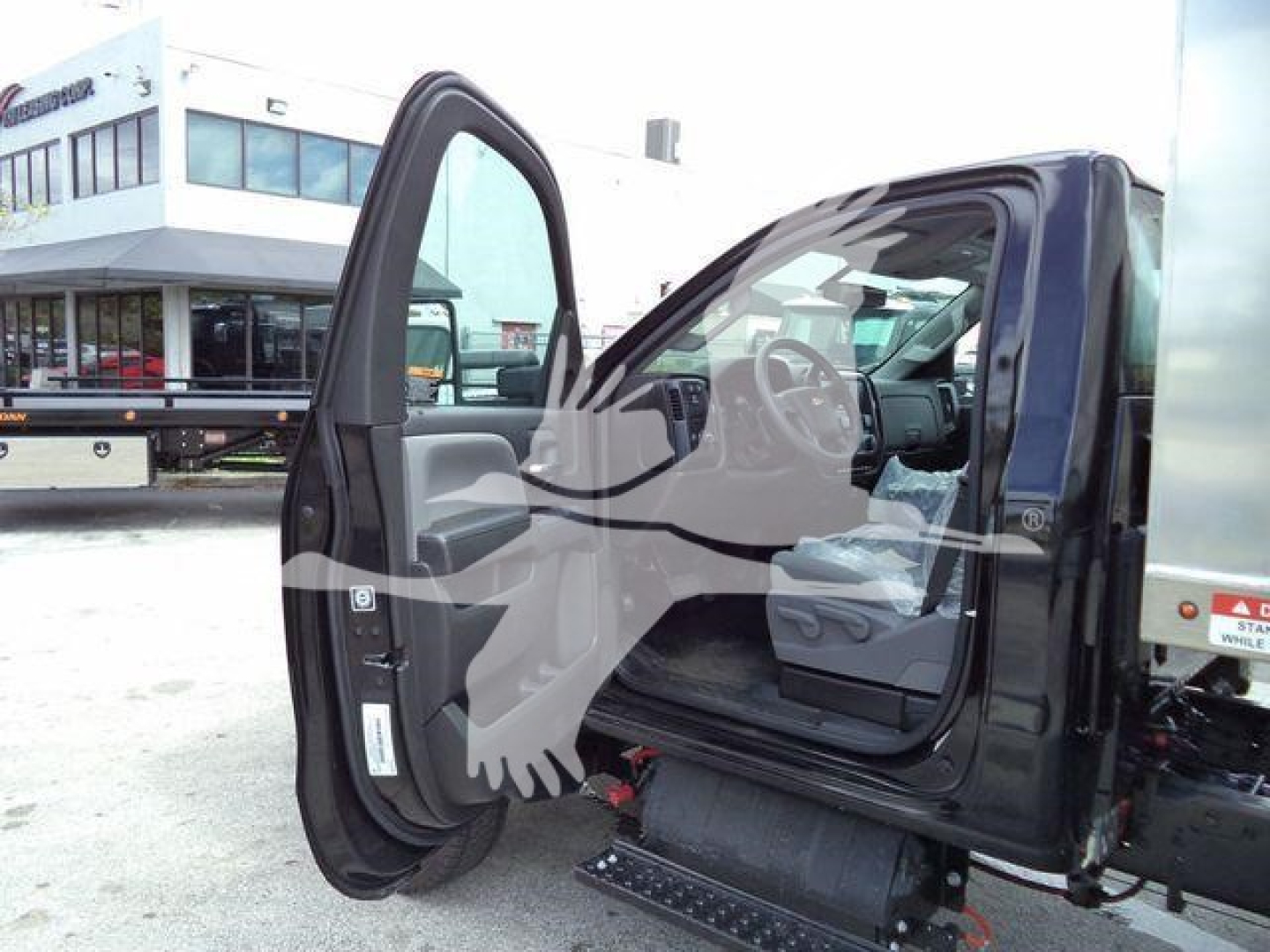 Vehicle cab interior with open driver door on a 2023 Chevrolet Silverado 6500HD; visible steps under the door