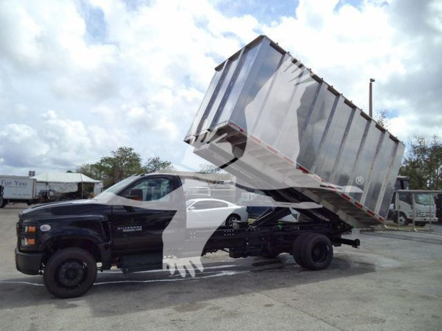 Truck with dump bed tilted up, Chevrolet Silverado 6500HD utility/dump truck in a dealership lot.