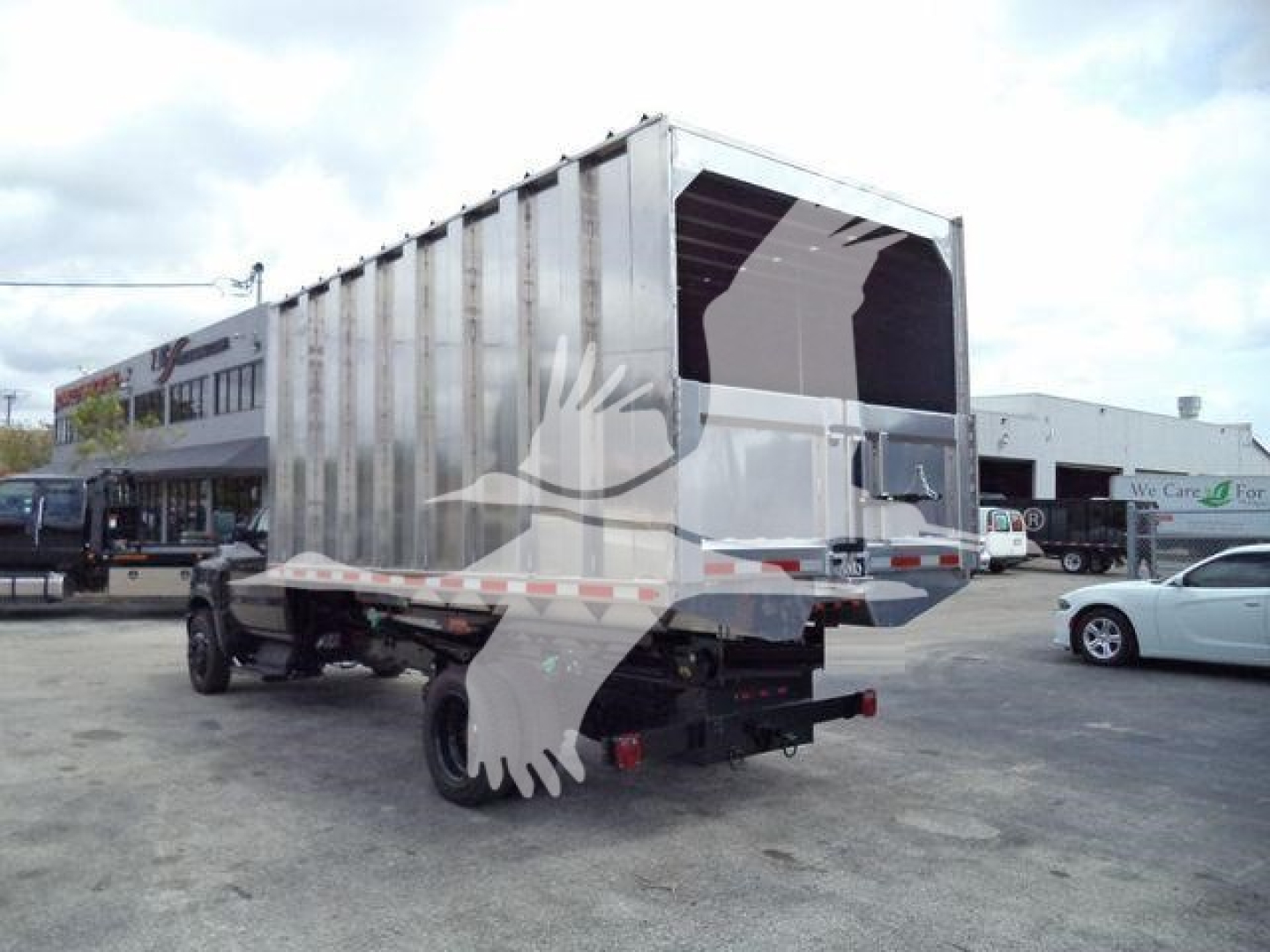 Truck bed with a large metal cargo trailer mounted on a Silverado chassis, rear view showing open tailgate and dual rear tires.