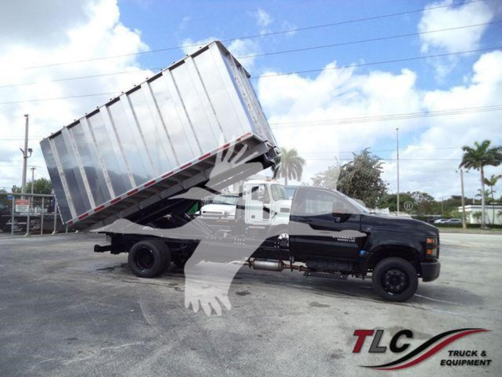 Chevrolet Silverado 6500HD dump truck in a tilted bed position, black cab with long chassis, large silver dump body raised for dumping.