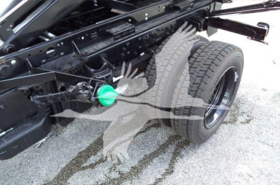 Truck rear suspension with dual rear wheels and green fuel cap visible; chassis and axles exposed, part of a 2023 Chevrolet Silverado 6500HD truck chassis.