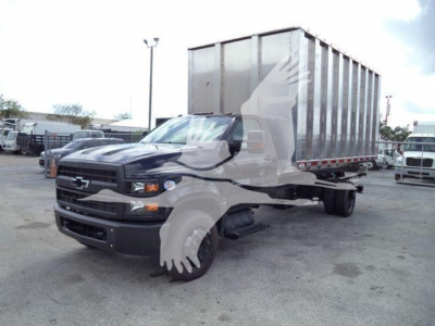 Chevrolet Silverado 6500HD chassis-cab truck with a large dump trailer in a lot, front grille and Chevrolet emblem visible.