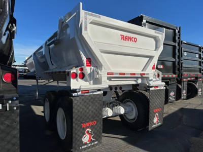 Ranco ED26-34 dump trailer rear showing RANCO logo, dual axles, reflective tape, and mud flaps with dinosaur graphic.