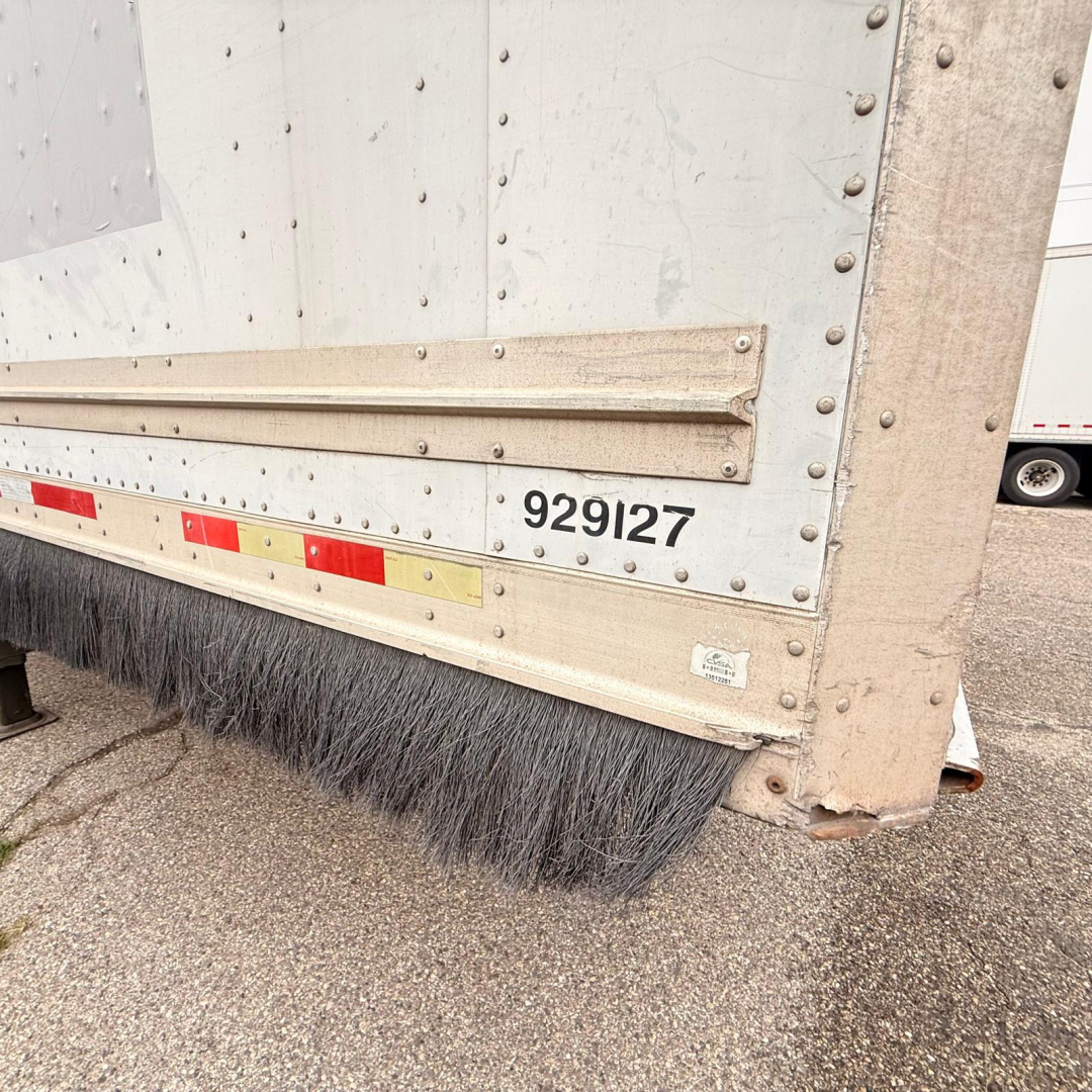 Trailer side view showing Great Dane 7441 SL dry van with lower edge brush seal and metal riveted paneling; visible serial 929127 and reflective striping.